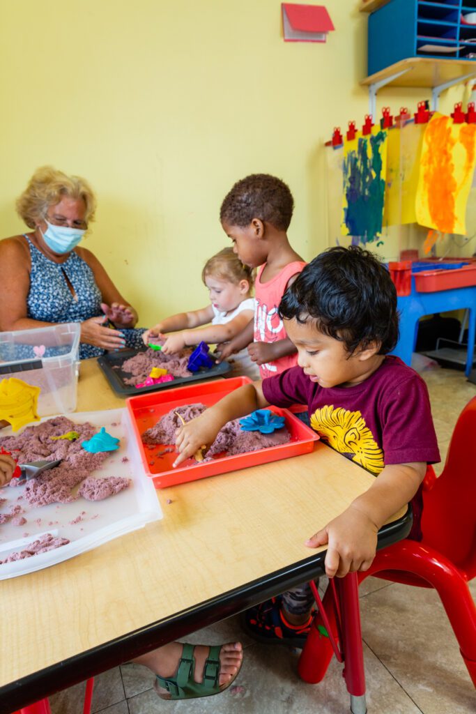Children engaged in a creative play activity with an adult supervising.