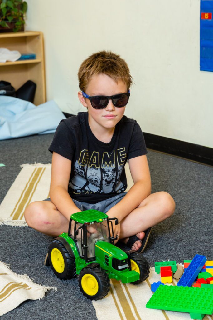 Young boy playing with a toy tractor indoors.